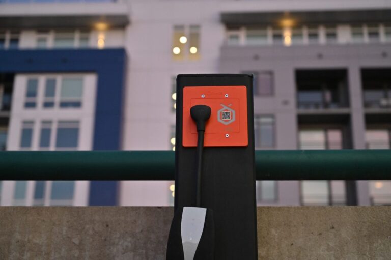 Orange Charger's Level 2 outlet sits installed in an apartment parking lot.